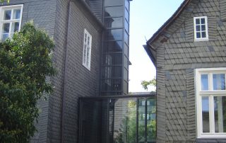 Außenaufzug installiert zwischen zwei schindelgedeckten Häusern