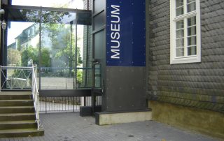 Außenaufzug neben einem schindelgedecktem Museumsbau