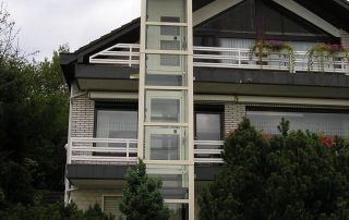 Weißer Glasaufzug bis ins Dachgeschoss eines Hauses