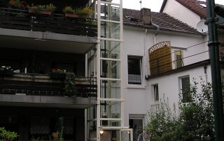 Weißer Glasaufzug neben Balkonen installiert