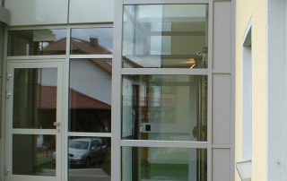 Außenaufzug aus Glas neben Glaseingang