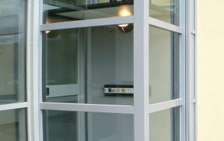Zugang zum Außenaufzug Glas und weiß