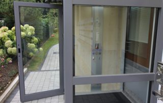 Eingang zu einem Außenaufzug aus Glas vom Gehweg aus